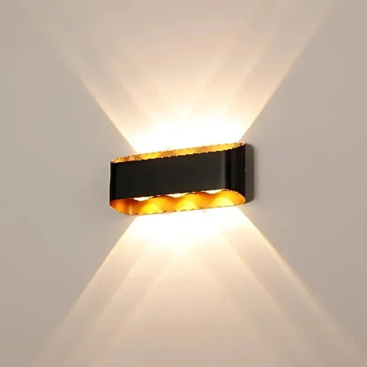 Modern black and gold wall sconce with warm upward and downward lighting for contemporary interiors