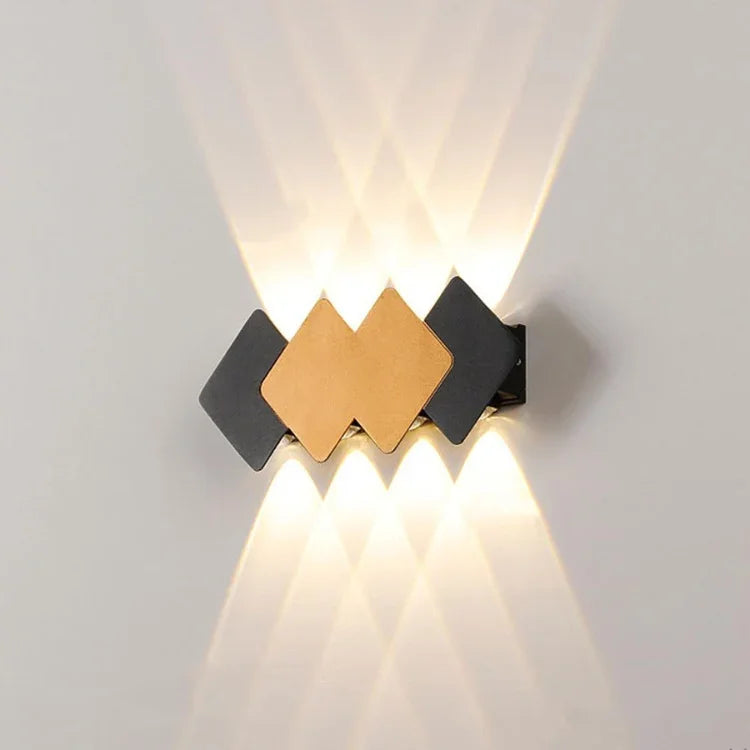 Modern wall sconce with geometric black and gold panels casting upward and downward light beams