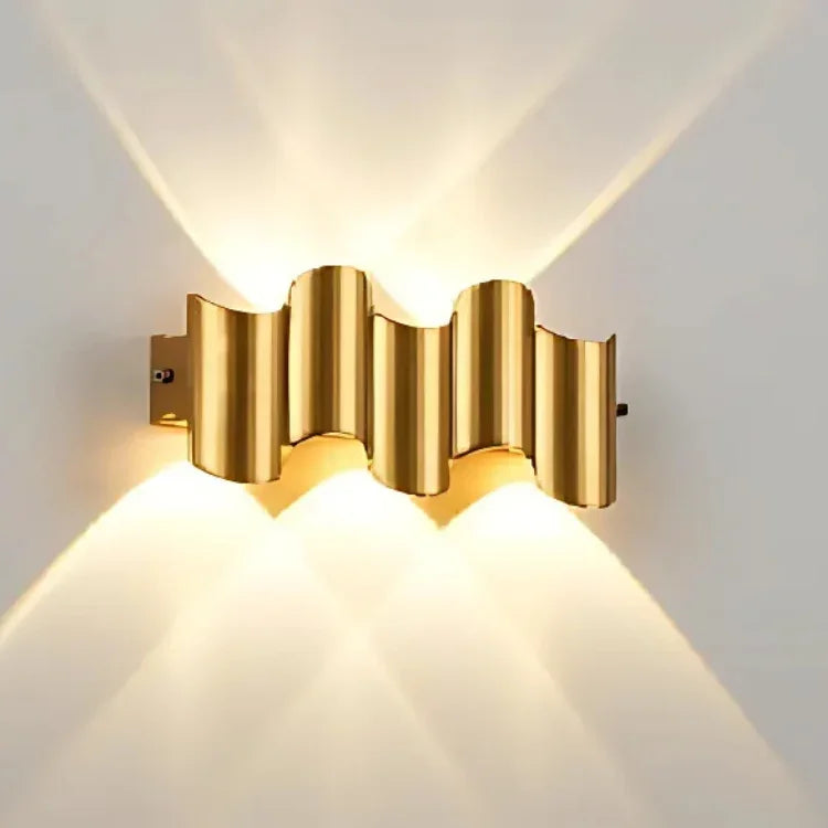 Modern gold wall sconce with wavy design, casting warm ambient light for contemporary interior decor